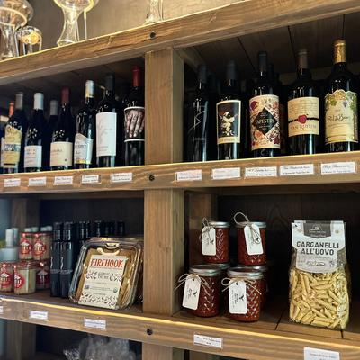 Wine bottles and gourmet food products displayed on wooden shelves.