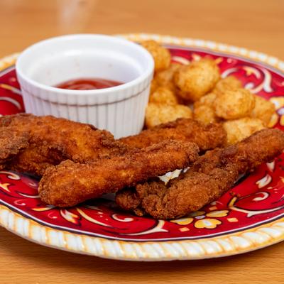 Chicken tenders served with dip and side of tater tots.