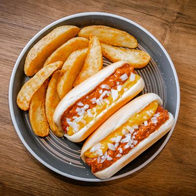 Hot Dog with chili cheese, served with potato wedges, top view.