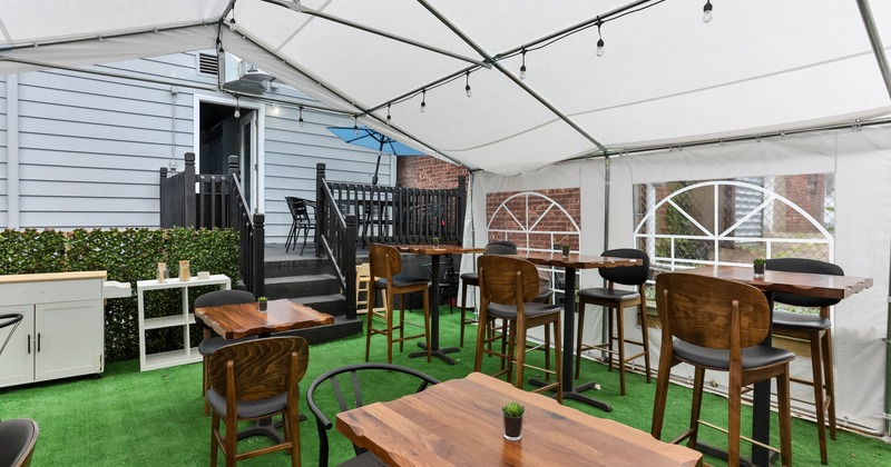 Exterior, seating area under a large white tent, artificial grass floor, restaurant back door