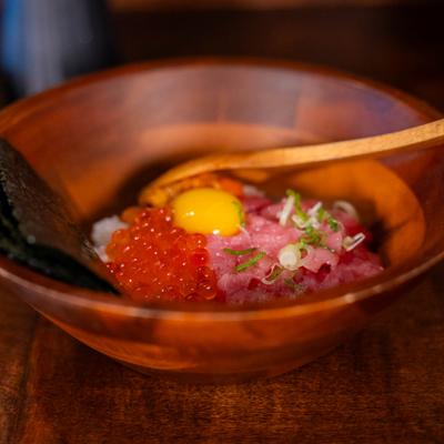 Japanese tuna tartare topped with salmon roe and egg yolk in a wooden bowl.
