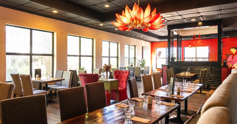 Interior, wooden tables, upholstered chairs, large windows, a lotus shaped orange pendant light