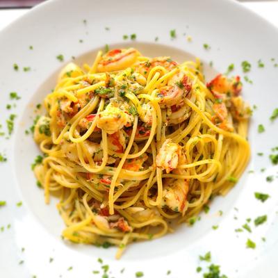 A plate of spaghetti with shrimp, garnished with fresh herbs.