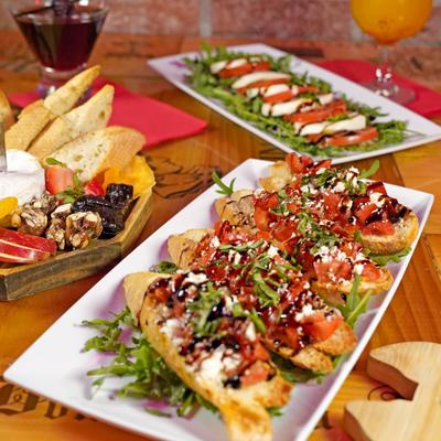 Tomato Bruschetta appetizer, accompanied by a charcuterie board and caprese salad.