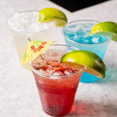 Three colorful cocktails garnished with lime wedges.