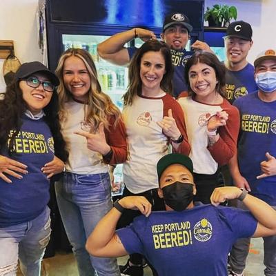 Three staff members posing with a group of people dressed in shirts with 