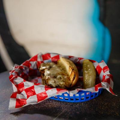 Philly cheese steak sandwich served with a pickle