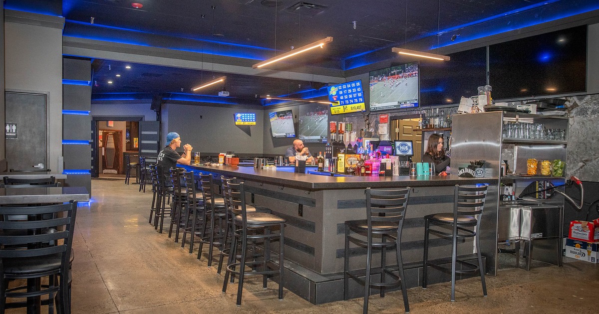 Bar area with guests watching sports on multiple TV screens