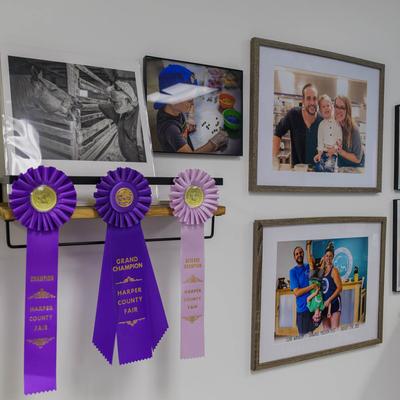 Framed photos and award ribbons on a white wall.