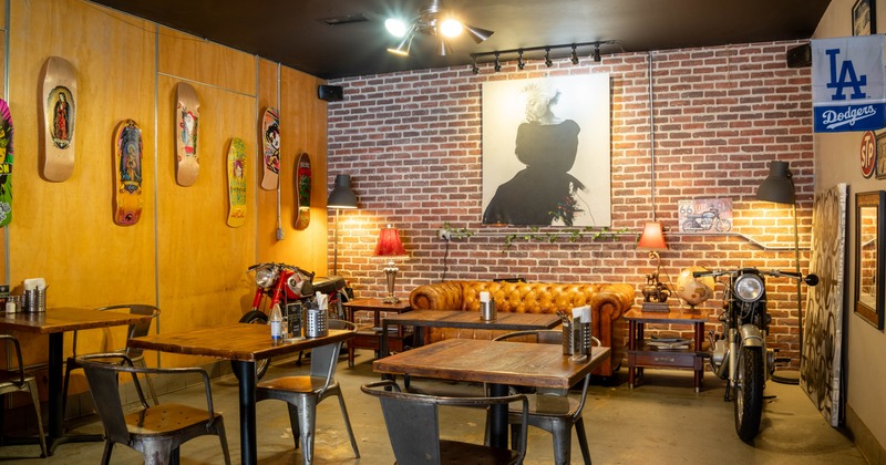 Interior with brick and wood walls, skateboards, vintage leather sofa, motorcycles, and soft lighting