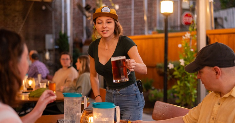 Server serving beer at an outdoor patio