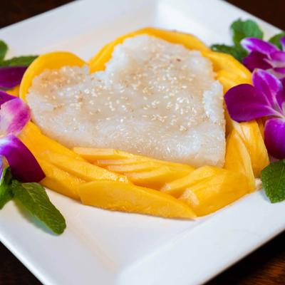 Heart-shaped mango sticky rice with purple orchid garnish.