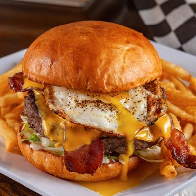 Egg and Bacon Burger served with French fries on a white plate.