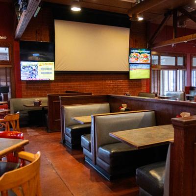 Interior with booth and table seating and several screens on the wall.