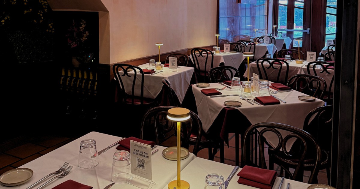 Elegantly set tables with white tablecloths, marron napkins, glasses, and table lamps