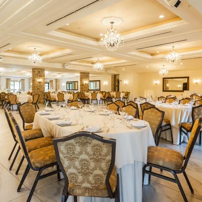 Interior with tabes set for dining, crystal chandeliers and rugged stone walls.