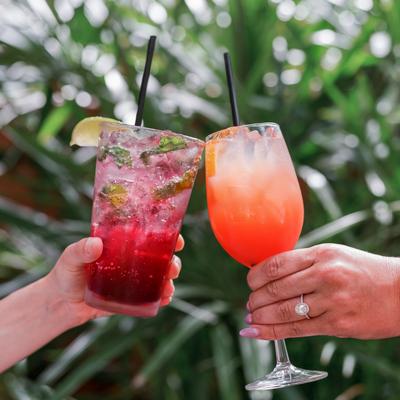 Two hands toasting with cocktails