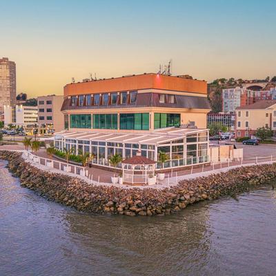 Exterior, modern restaurant building with extensive glass walls overlooking the river.