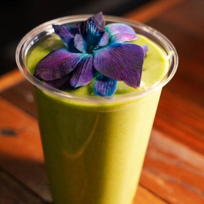 Green smoothie topped with purple flower.