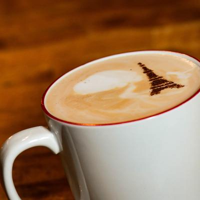A cup of latte with an Eiffel Tower cinnamon design on the foam.