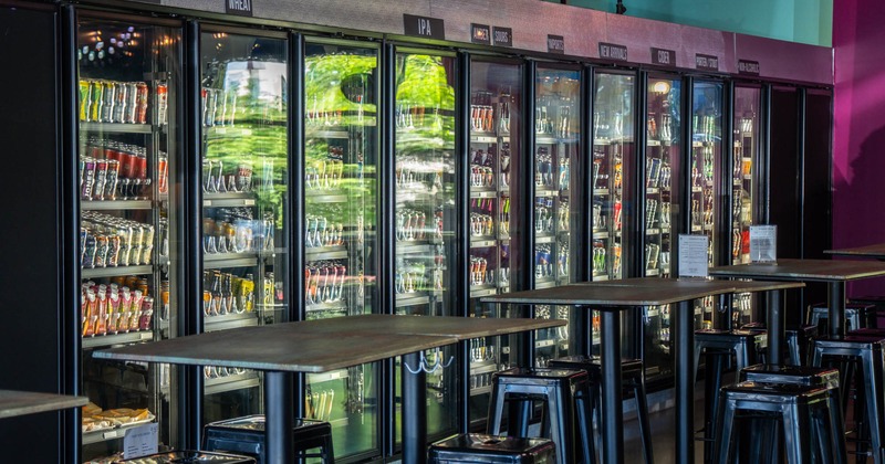 Interior, bar tables and stools, fridges with drinks