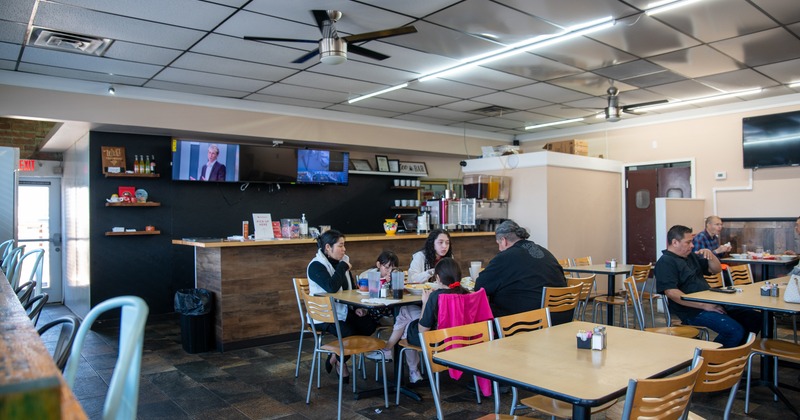 Diner tables, chairs, food counter behind, screens above