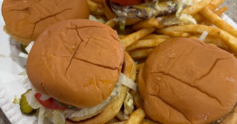 Four burgers surrounded by fries on a platter