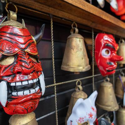 Colorful masks and bronze bells on a wooden display.