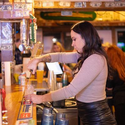 A bartender pouring a drink behind a counter.
