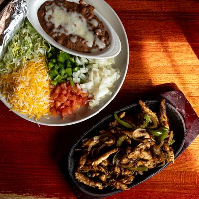 Grilled chicken Fajitas, served with chopped veggies, cheese, and beans.