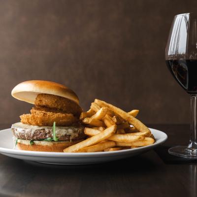 Burger with onion rings and a side of fries.