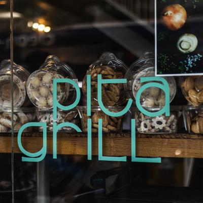 Assorted cookie jars displayed in a window with a Pita Grill sign.