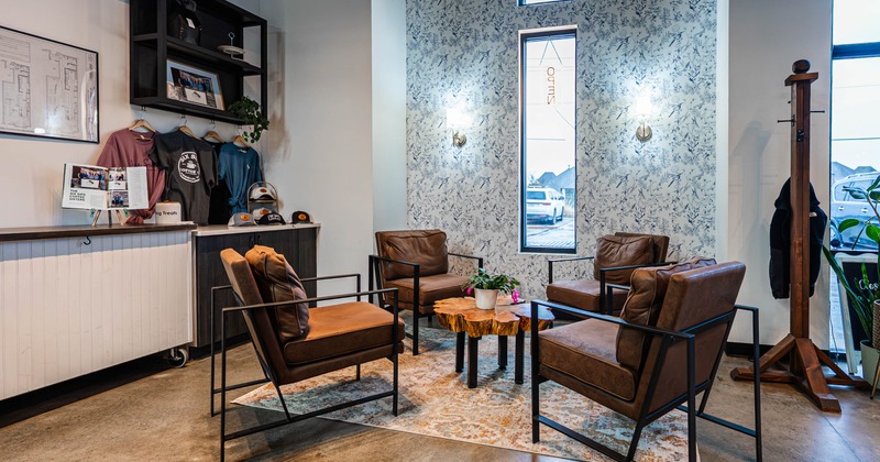 Modern waiting area with brown leather chairs, a wooden coffee table, and floral wallpaper