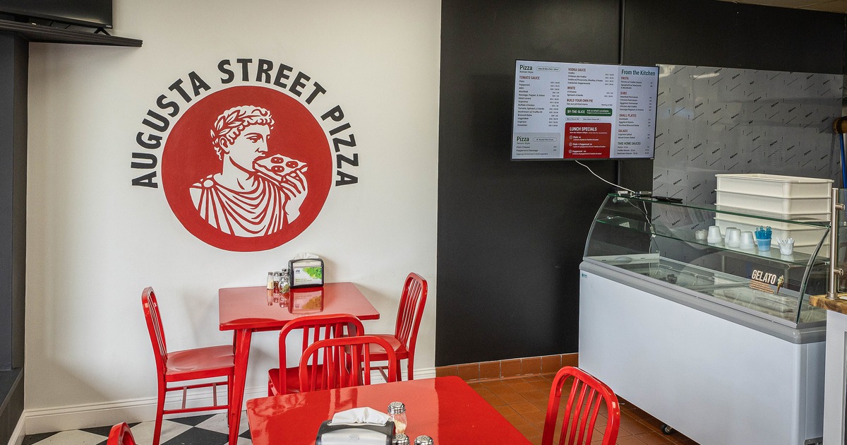 Interior of pizzeria dining area with red tables and chairs
