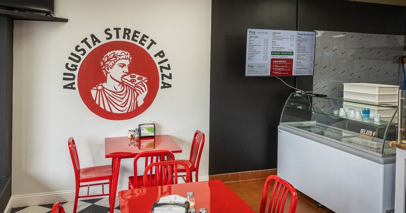 Interior of pizzeria dining area with red tables and chairs