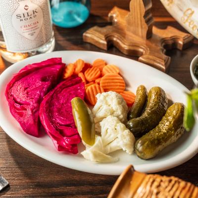Plate of assorted pickled vegetables featuring red cabbage, carrots, cauliflower and cucumbers.