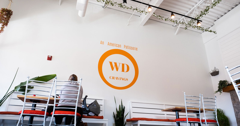 WD Cravings logo on the wall above the table with a guest