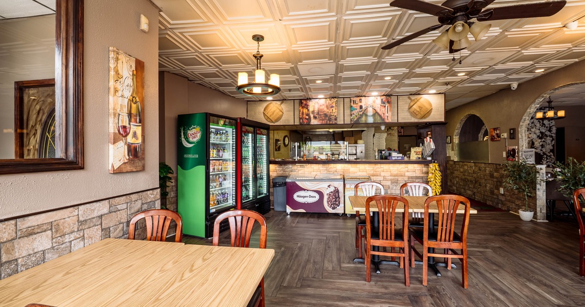 Interior of a cafe with wooden tables and chairs, a green drink refrigerator, and a service counter