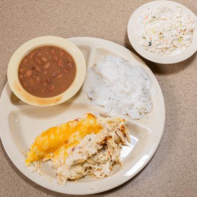 Shredded chicken with cheese sauce, rice, gravy, and beans.
