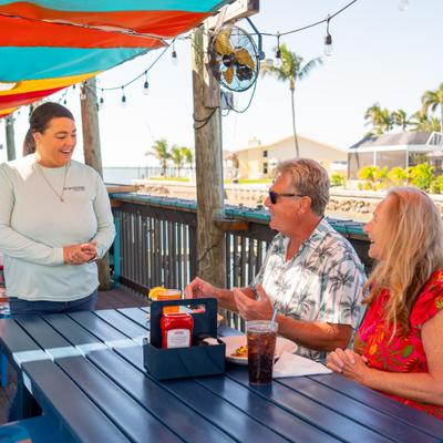 A server speaking with two diners at an  outdoor table.