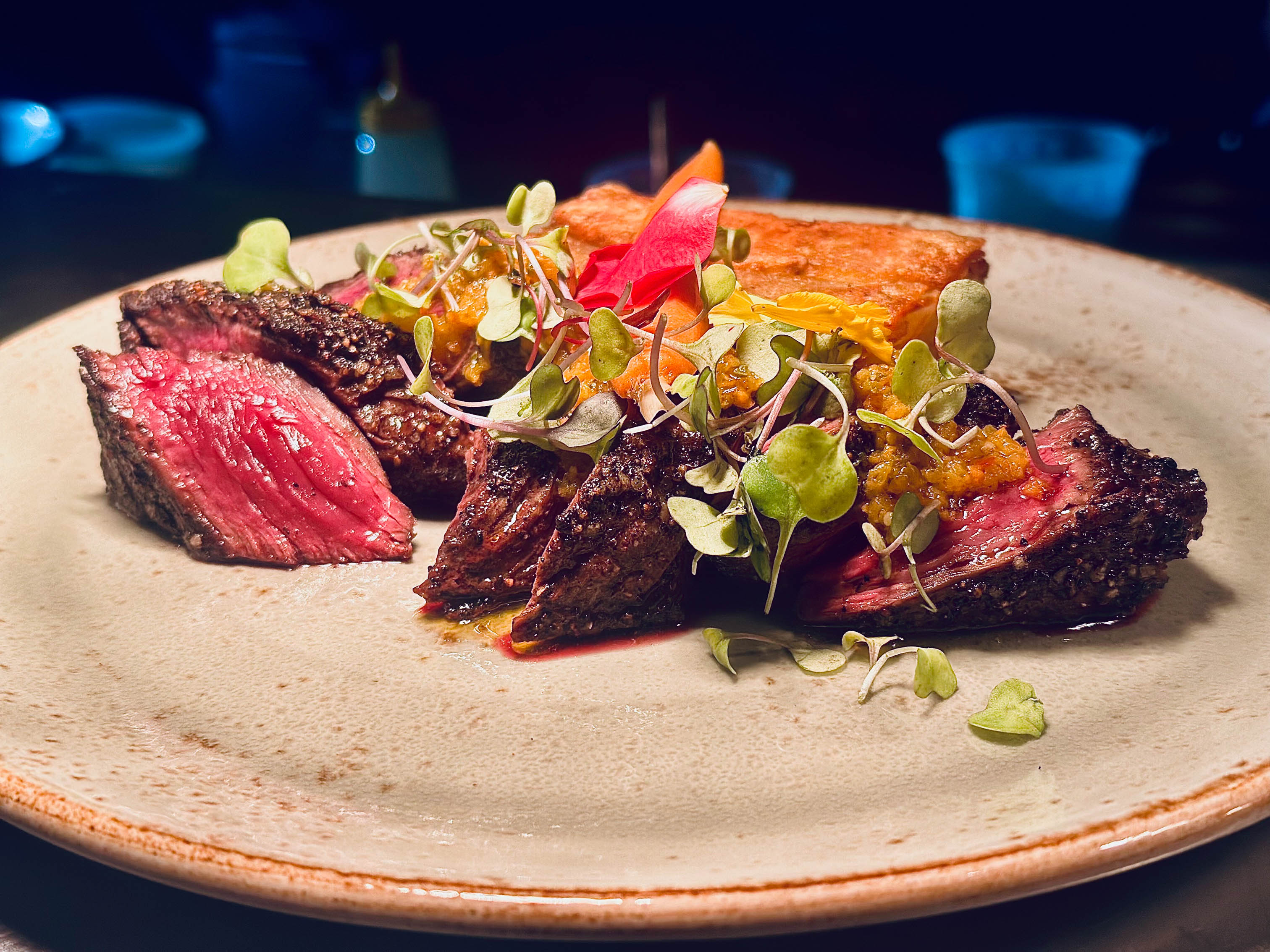 Sliced medium-rare steak served with microgreens and cornbread