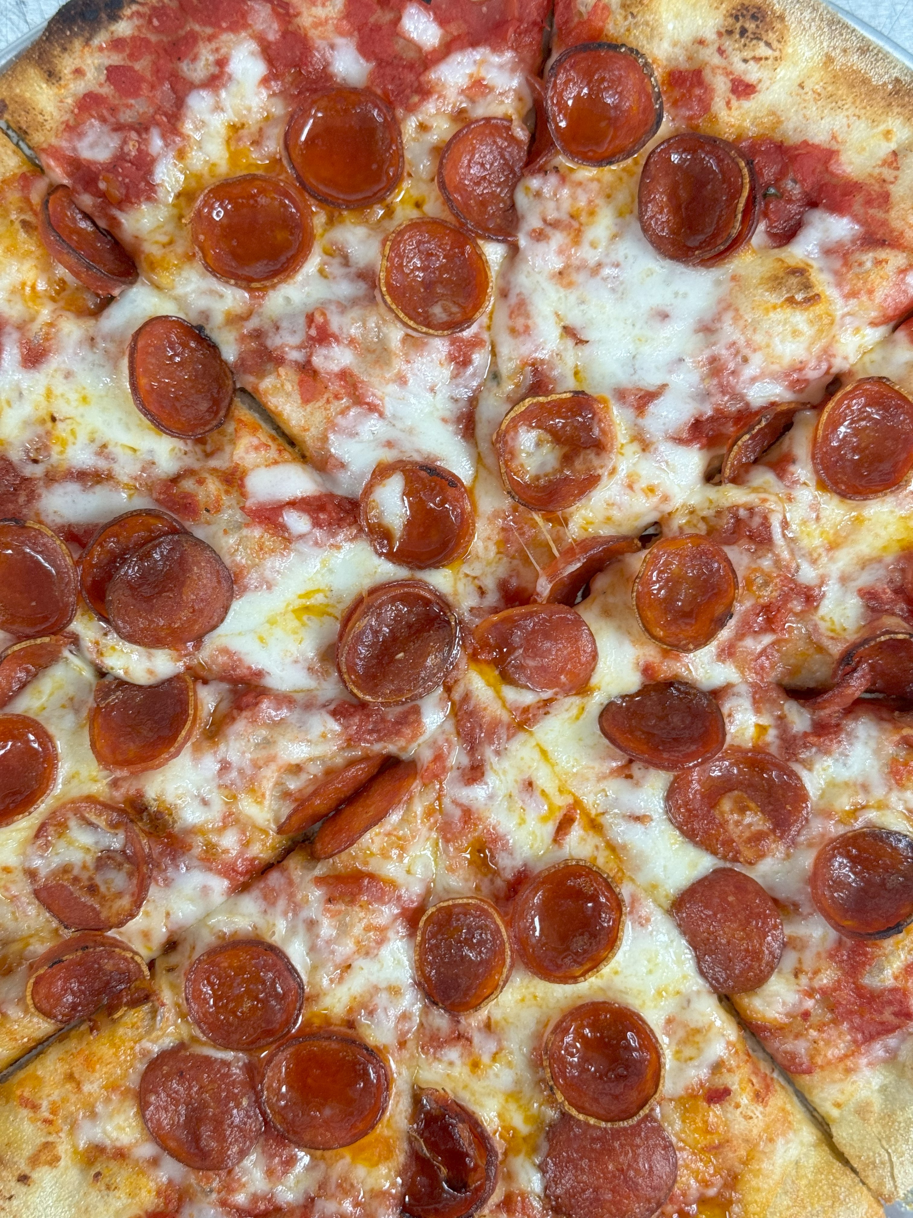 A close up picture of a pizza with small pepperonis on it