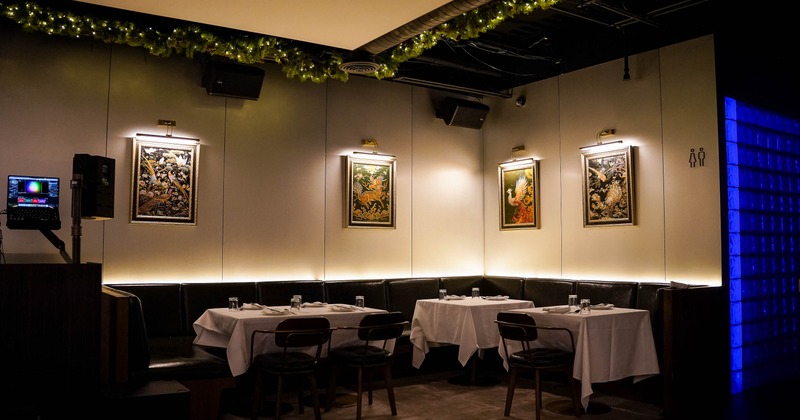Interior with tables, framed artwork, garland lighting and a blue-lit wall.