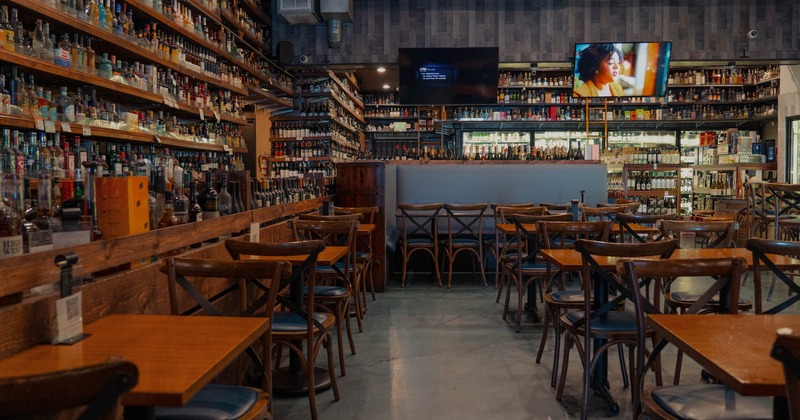 Booths, tables, and chairs with a bar on the right side