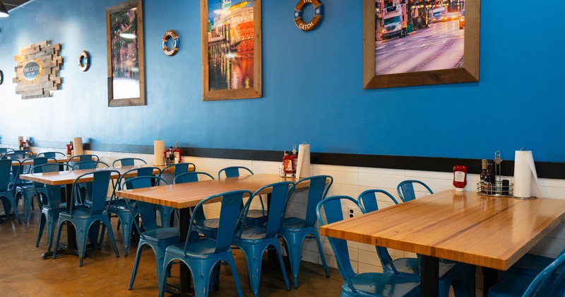 Interior with blue walls, wooden tables and blue metal chairs