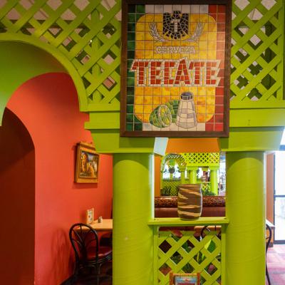 Tiled beer sign on a green arched structure in a restaurant.