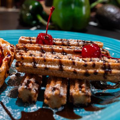 Churros topped with cherries and chocolate sauce.