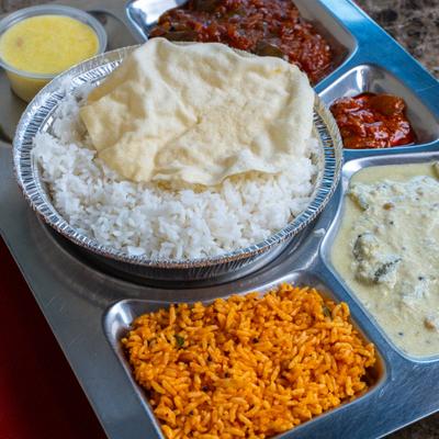 A platter with a dish of rice cooked in boiling milk and various side dishes.