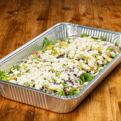 Fresh salad topped with cheese in a foil container.