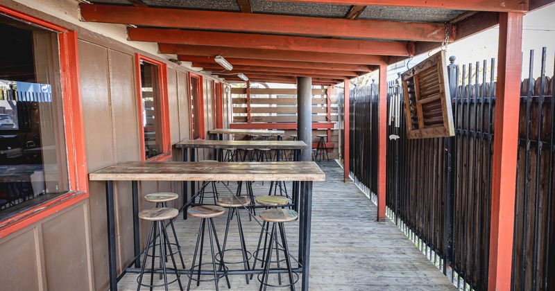 Exterior, patio, covered seating area, bar stools and tables, windows on the left